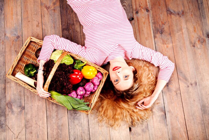 Chica con una cesta llena de verduras.